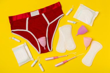 Aybaşı kupası, parlak bir arka plan. Hijyenik peçeteler, tamponlar ve regl kupası. Kritik günler, regl dönemi kavramı. Kadın hijyen ürünü. Kadın sağlığı kavramı. Adet öncesi sendromu. Boşluğu kopyala