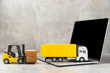 Parlak desenli arka planda sarı forklift. Lojistik konsept. Online alışveriş konsepti için lojistik ve tedarik zinciri yönetimi. Mağazaya mal ya da ürün teslimatı. Karton kutu.