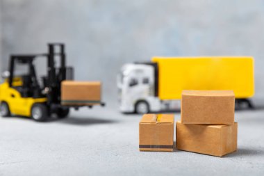 Parlak desenli arka planda sarı forklift. Lojistik konsept. Online alışveriş konsepti için lojistik ve tedarik zinciri yönetimi. Mağazaya mal ya da ürün teslimatı. Karton kutu.