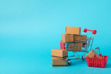 Çevrimiçi alışveriş kavramı. Karton kutu ve parlak renkli bir arka planda tramvayda alışveriş poşetleri. Alışveriş sepeti. İnternetten bilgisayar, tablet, telefon ve kredi kartı kullanarak alışveriş. Eve teslim.