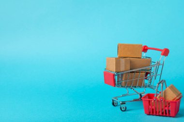 Çevrimiçi alışveriş kavramı. Karton kutu ve parlak renkli bir arka planda tramvayda alışveriş poşetleri. Alışveriş sepeti. İnternetten bilgisayar, tablet, telefon ve kredi kartı kullanarak alışveriş. Eve teslim.