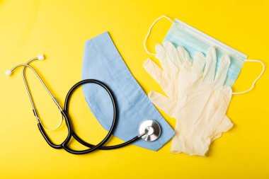 Tıbbi nitril eldivenler, mavi başlık, desenli arka planda tek kullanımlık tıbbi maske. Tıbbi koruyucu giysi. Cerrahi lateks eldivenler. Lastik eldiven üretimi. Tıp konsepti. Üst Manzara. Metni kopyala