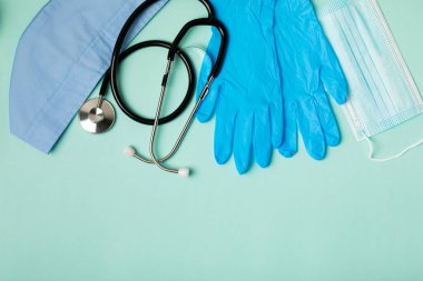 Tıbbi nitril eldivenler, mavi başlık, desenli arka planda tek kullanımlık tıbbi maske. Tıbbi koruyucu giysi. Cerrahi lateks eldivenler. Lastik eldiven üretimi. Tıp konsepti. Üst Manzara. Metni kopyala