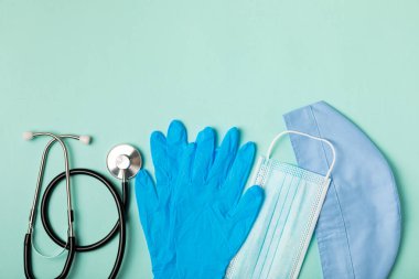 Tıbbi nitril eldivenler, mavi başlık, desenli arka planda tek kullanımlık tıbbi maske. Tıbbi koruyucu giysi. Cerrahi lateks eldivenler. Lastik eldiven üretimi. Tıp konsepti. Üst Manzara. Metni kopyala