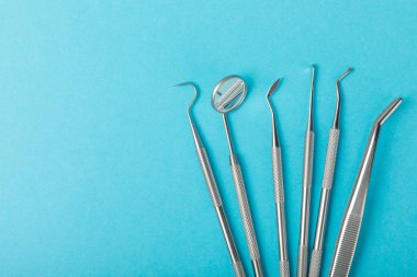 Mavi arkaplandaki dişçi aletleri. Diş hekimi konsepti. Diş bakımı, diş sağlığı konsepti. Ağız boşluğuna dikkat etmek anlamına geliyor. Diş modeli ve dişçi aletleri. Diş hijyeni. Mesaj için yer var. Boşluğu kopyala.