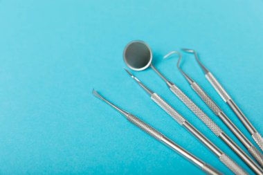 Mavi arkaplandaki dişçi aletleri. Diş hekimi konsepti. Diş bakımı, diş sağlığı konsepti. Ağız boşluğuna dikkat etmek anlamına geliyor. Diş modeli ve dişçi aletleri. Diş hijyeni. Mesaj için yer var. Boşluğu kopyala.