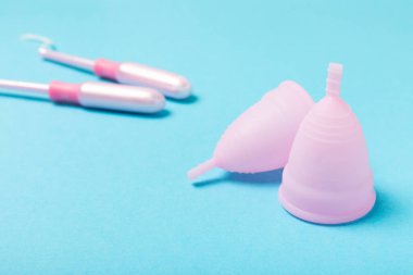 Aybaşı bardağı parlak bir arka planda. Hijyenik peçeteler, tamponlar ve regl kupası. Kritik günler, regl dönemi kavramı. Kadın hijyen ürünü. Kadın sağlığı kavramı. Adet öncesi sendromu. Boşluğu kopyala