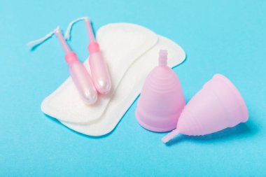 Aybaşı bardağı parlak bir arka planda. Hijyenik peçeteler, tamponlar ve regl kupası. Kritik günler, regl dönemi kavramı. Kadın hijyen ürünü. Kadın sağlığı kavramı. Adet öncesi sendromu. Boşluğu kopyala