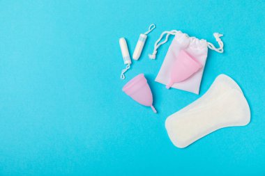 Aybaşı bardağı parlak bir arka planda. Hijyenik peçeteler, tamponlar ve regl kupası. Kritik günler, regl dönemi kavramı. Kadın hijyen ürünü. Kadın sağlığı kavramı. Adet öncesi sendromu. Boşluğu kopyala