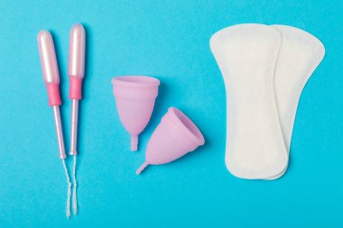 Aybaşı bardağı parlak bir arka planda. Hijyenik peçeteler, tamponlar ve regl kupası. Kritik günler, regl dönemi kavramı. Kadın hijyen ürünü. Kadın sağlığı kavramı. Adet öncesi sendromu. Boşluğu kopyala