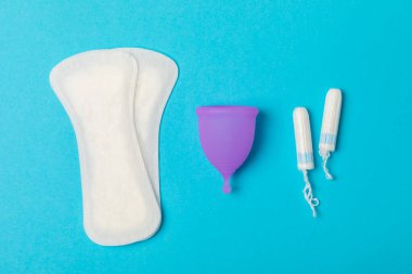 Aybaşı bardağı parlak bir arka planda. Hijyenik peçeteler, tamponlar ve regl kupası. Kritik günler, regl dönemi kavramı. Kadın hijyen ürünü. Kadın sağlığı kavramı. Adet öncesi sendromu. Boşluğu kopyala