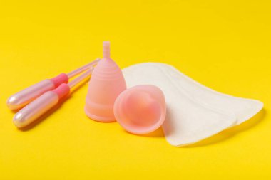 Aybaşı bardağı parlak bir arka planda. Hijyenik peçeteler, tamponlar ve regl kupası. Kritik günler, regl dönemi kavramı. Kadın hijyen ürünü. Kadın sağlığı kavramı. Adet öncesi sendromu. Boşluğu kopyala