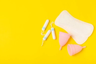 Aybaşı bardağı parlak bir arka planda. Hijyenik peçeteler, tamponlar ve regl kupası. Kritik günler, regl dönemi kavramı. Kadın hijyen ürünü. Kadın sağlığı kavramı. Adet öncesi sendromu. Boşluğu kopyala