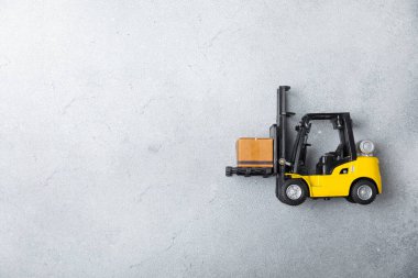 Sarı forklift ve parlak arka planda sarı kamyon. Lojistik konsept. Online alışveriş için lojistik ve tedarik zinciri yönetimi. Mağazaya mal ya da ürün teslimatı. Karton kutu..