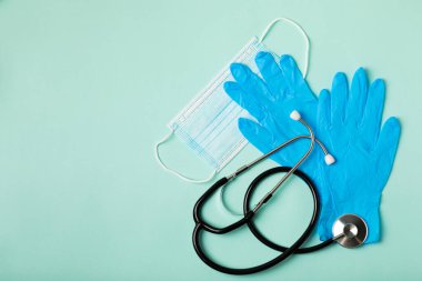 Tıbbi nitril eldivenler, mavi başlık, desenli arka planda tek kullanımlık tıbbi maske. Tıbbi koruyucu giysi. Cerrahi lateks eldivenler. Lastik eldiven üretimi. Tıp konsepti. Üst Manzara. Metni kopyala