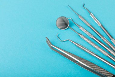 Mavi arkaplandaki dişçi aletleri. Diş hekimi konsepti. Diş bakımı, diş sağlığı konsepti. Ağız boşluğuna dikkat etmek anlamına geliyor. Diş modeli ve dişçi aletleri. Diş hijyeni. Mesaj için yer var. Boşluğu kopyala.