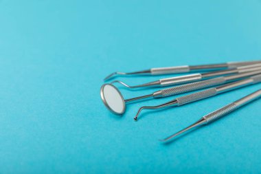 Mavi arkaplandaki dişçi aletleri. Diş hekimi konsepti. Diş bakımı, diş sağlığı konsepti. Ağız boşluğuna dikkat etmek anlamına geliyor. Diş modeli ve dişçi aletleri. Diş hijyeni. Mesaj için yer var. Boşluğu kopyala.