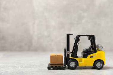 Sarı forklift ve parlak arka planda sarı kamyon. Lojistik konsept. Online alışveriş için lojistik ve tedarik zinciri yönetimi. Mağazaya mal ya da ürün teslimatı. Karton kutu..