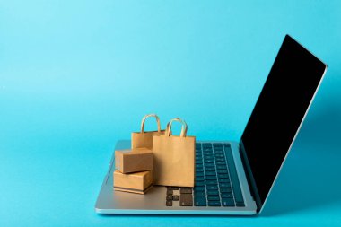 Çevrimiçi alışveriş kavramı. Karton kutu ve parlak renkli bir arka planda tramvayda alışveriş poşetleri. Alışveriş sepeti. İnternetten bilgisayar, tablet, telefon ve kredi kartı kullanarak alışveriş. Eve teslim.