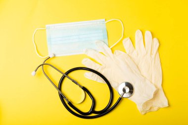 Tıbbi nitril eldivenler, mavi başlık, desenli arka planda tek kullanımlık tıbbi maske. Tıbbi koruyucu giysi. Cerrahi lateks eldivenler. Lastik eldiven üretimi. Tıp konsepti. Üst Manzara. Metni kopyala