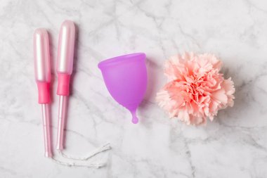 Aybaşı bardağı parlak bir arka planda. Hijyenik peçeteler, tamponlar ve regl kupası. Kritik günler, regl dönemi kavramı. Kadın hijyen ürünü. Kadın sağlığı kavramı. Adet öncesi sendromu. Boşluğu kopyala