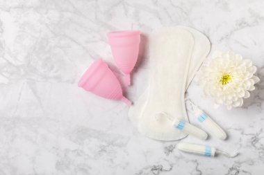 Aybaşı bardağı parlak bir arka planda. Hijyenik peçeteler, tamponlar ve regl kupası. Kritik günler, regl dönemi kavramı. Kadın hijyen ürünü. Kadın sağlığı kavramı. Adet öncesi sendromu. Boşluğu kopyala