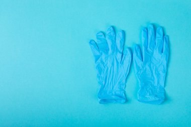 Tıbbi nitril eldivenler, mavi başlık, desenli arka planda tek kullanımlık tıbbi maske. Tıbbi koruyucu giysi. Cerrahi lateks eldivenler. Lastik eldiven üretimi. Tıp konsepti. Üst Manzara. Metni kopyala