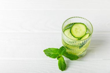 Salatalık suyu, limon, nane ve ahşap bir masada. İçme bardağında dilimlenmiş salatalık ile karıştırılmış su. Tonik ferahlatıcı bir içecek. Salatalık limonata. Doğal soğutma içeceği. Boşluğu kopyala.