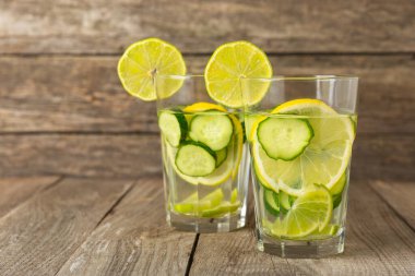 Salatalık suyu, limon, nane ve ahşap bir masada. İçme bardağında dilimlenmiş salatalık ile karıştırılmış su. Tonik ferahlatıcı bir içecek. Salatalık limonata. Doğal soğutma içeceği. Boşluğu kopyala.