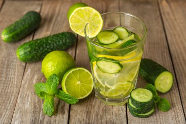 Salatalık suyu, limon, nane ve ahşap bir masada. İçme bardağında dilimlenmiş salatalık ile karıştırılmış su. Tonik ferahlatıcı bir içecek. Salatalık limonata. Doğal soğutma içeceği. Boşluğu kopyala.