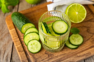 Salatalık suyu, limon, nane ve ahşap bir masada. İçme bardağında dilimlenmiş salatalık ile karıştırılmış su. Tonik ferahlatıcı bir içecek. Salatalık limonata. Doğal soğutma içeceği. Boşluğu kopyala.
