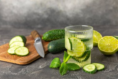 Salatalık suyu, limon, nane ve ahşap bir masada. İçme bardağında dilimlenmiş salatalık ile karıştırılmış su. Tonik ferahlatıcı bir içecek. Salatalık limonata. Doğal soğutma içeceği. Boşluğu kopyala.