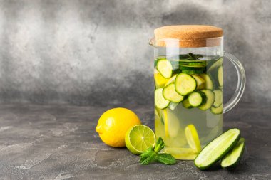 Salatalık suyu, limon, nane ve ahşap bir masada. İçme bardağında dilimlenmiş salatalık ile karıştırılmış su. Tonik ferahlatıcı bir içecek. Salatalık limonata. Doğal soğutma içeceği. Boşluğu kopyala.