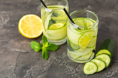 Salatalık suyu, limon, nane ve ahşap bir masada. İçme bardağında dilimlenmiş salatalık ile karıştırılmış su. Tonik ferahlatıcı bir içecek. Salatalık limonata. Doğal soğutma içeceği. Boşluğu kopyala.