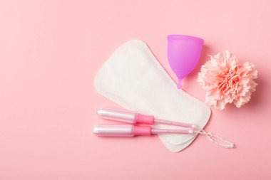 Aybaşı bardağı parlak bir arka planda. Hijyenik peçeteler, tamponlar ve regl kupası. Kritik günler, regl dönemi kavramı. Kadın hijyen ürünü. Kadın sağlığı kavramı. Adet öncesi sendromu. Boşluğu kopyala