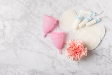 Aybaşı bardağı parlak bir arka planda. Hijyenik peçeteler, tamponlar ve regl kupası. Kritik günler, regl dönemi kavramı. Kadın hijyen ürünü. Kadın sağlığı kavramı. Adet öncesi sendromu. Boşluğu kopyala