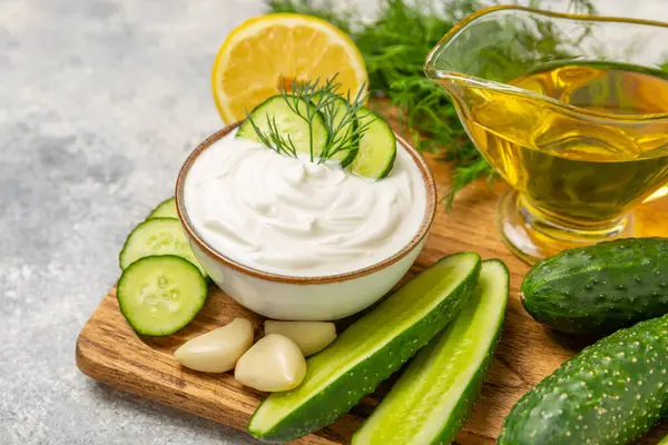 Ahşap bir masada salatalık kremalı tzatziki sosu. Tatar sosu. Geleneksel lezzetli aperatif. Yoğurt sosu. Tzatziki, salatalık, sarımsak, dereotu, limon, nane. Salata sosu. Kopya alanı.