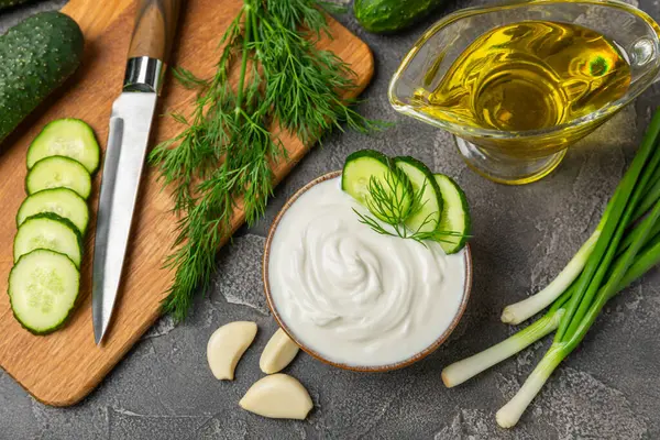 Ahşap bir masada salatalık kremalı tzatziki sosu. Tatar sosu. Geleneksel lezzetli aperatif. Yoğurt sosu. Tzatziki, salatalık, sarımsak, dereotu, limon, nane. Salata sosu. Kopya alanı.