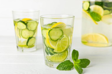 Salatalık suyu, limon, nane ve ahşap bir masada. İçme bardağında dilimlenmiş salatalık ile karıştırılmış su. Tonik ferahlatıcı bir içecek. Salatalık limonata. Doğal soğutma içeceği. Boşluğu kopyala.