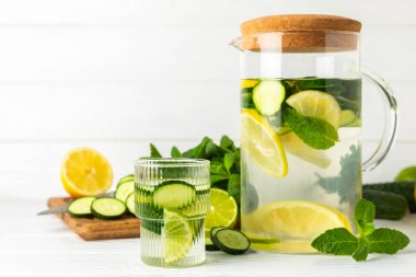 Salatalık suyu, limon, nane ve ahşap bir masada. İçme bardağında dilimlenmiş salatalık ile karıştırılmış su. Tonik ferahlatıcı bir içecek. Salatalık limonata. Doğal soğutma içeceği. Boşluğu kopyala.