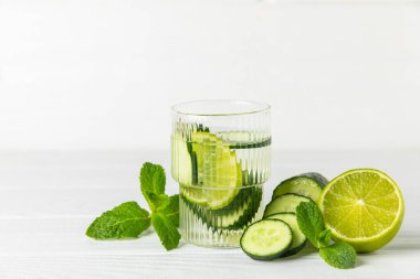 Salatalık suyu, limon, nane ve ahşap bir masada. İçme bardağında dilimlenmiş salatalık ile karıştırılmış su. Tonik ferahlatıcı bir içecek. Salatalık limonata. Doğal soğutma içeceği. Boşluğu kopyala.