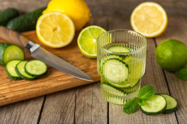 Salatalık suyu, limon, nane ve ahşap bir masada. İçme bardağında dilimlenmiş salatalık ile karıştırılmış su. Tonik ferahlatıcı bir içecek. Salatalık limonata. Doğal soğutma içeceği. Boşluğu kopyala.
