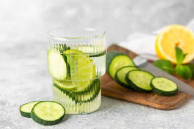 Salatalık suyu, limon, nane ve ahşap bir masada. İçme bardağında dilimlenmiş salatalık ile karıştırılmış su. Tonik ferahlatıcı bir içecek. Salatalık limonata. Doğal soğutma içeceği. Boşluğu kopyala.