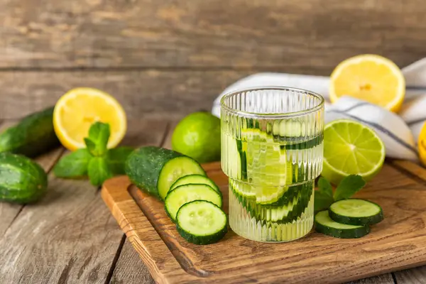 Salatalık suyu, limon, nane ve ahşap bir masada. İçme bardağında dilimlenmiş salatalık ile karıştırılmış su. Tonik ferahlatıcı bir içecek. Salatalık limonata. Doğal soğutma içeceği. Boşluğu kopyala.