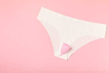 Aybaşı bardağı parlak bir arka planda. Hijyenik peçeteler, tamponlar ve regl kupası. Kritik günler, regl dönemi kavramı. Kadın hijyen ürünü. Kadın sağlığı kavramı. Adet öncesi sendromu. Boşluğu kopyala