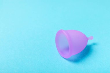 Aybaşı bardağı parlak bir arka planda. Hijyenik peçeteler, tamponlar ve regl kupası. Kritik günler, regl dönemi kavramı. Kadın hijyen ürünü. Kadın sağlığı kavramı. Adet öncesi sendromu. Boşluğu kopyala