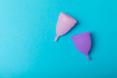 Aybaşı bardağı parlak bir arka planda. Hijyenik peçeteler, tamponlar ve regl kupası. Kritik günler, regl dönemi kavramı. Kadın hijyen ürünü. Kadın sağlığı kavramı. Adet öncesi sendromu. Boşluğu kopyala