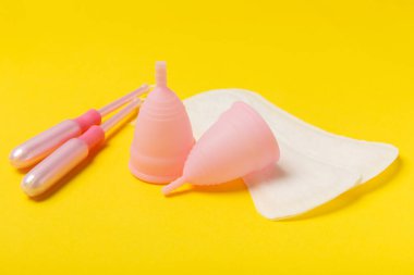 Aybaşı bardağı parlak bir arka planda. Hijyenik peçeteler, tamponlar ve regl kupası. Kritik günler, regl dönemi kavramı. Kadın hijyen ürünü. Kadın sağlığı kavramı. Adet öncesi sendromu. Boşluğu kopyala