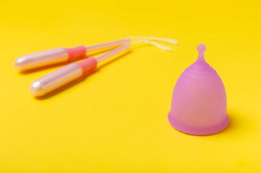 Aybaşı bardağı parlak bir arka planda. Hijyenik peçeteler, tamponlar ve regl kupası. Kritik günler, regl dönemi kavramı. Kadın hijyen ürünü. Kadın sağlığı kavramı. Adet öncesi sendromu. Boşluğu kopyala