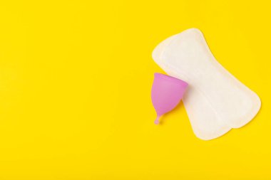 Aybaşı bardağı parlak bir arka planda. Hijyenik peçeteler, tamponlar ve regl kupası. Kritik günler, regl dönemi kavramı. Kadın hijyen ürünü. Kadın sağlığı kavramı. Adet öncesi sendromu. Boşluğu kopyala